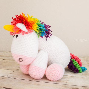 White crochet amigurumi unicorn and rainbow mane